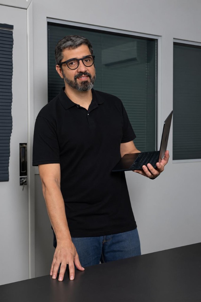 Co-fundador do Data Source Protocol, de pé junto a uma mesa, com um laptop na mão.